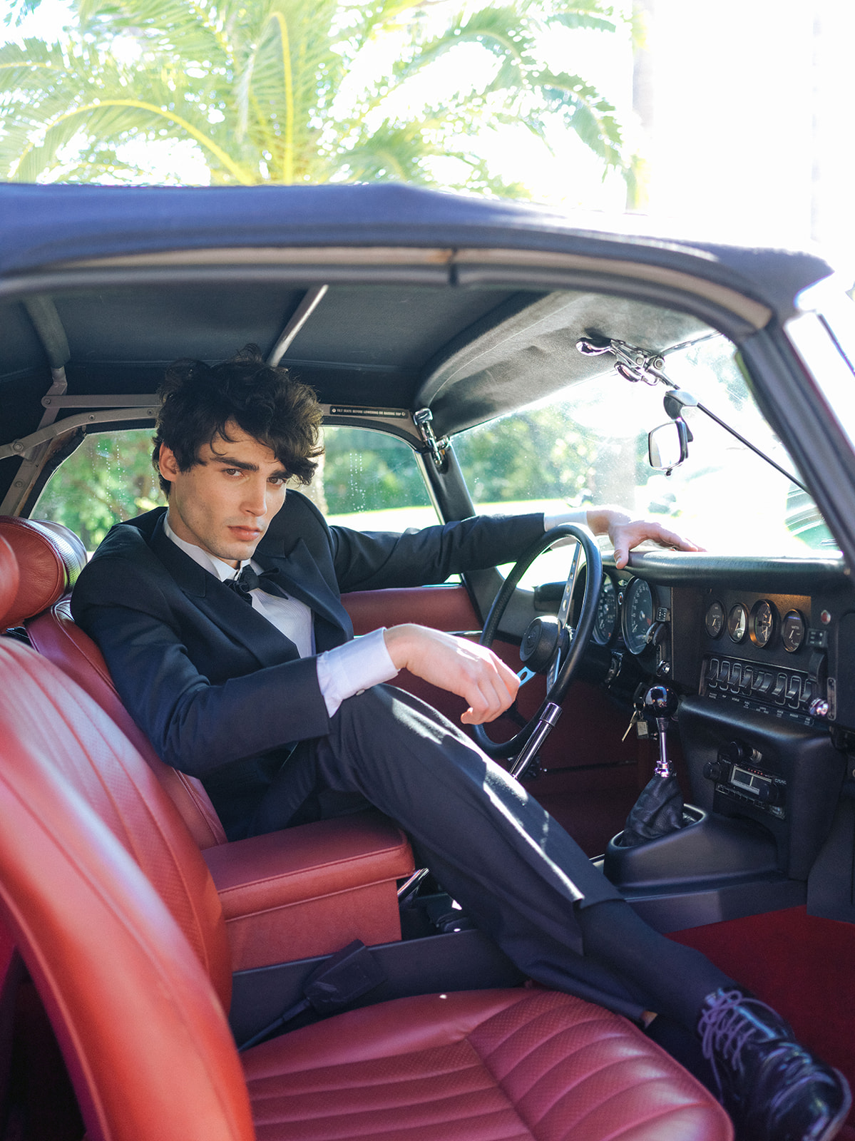 Color editorial portrait of a groom inside a vintage Jaguar